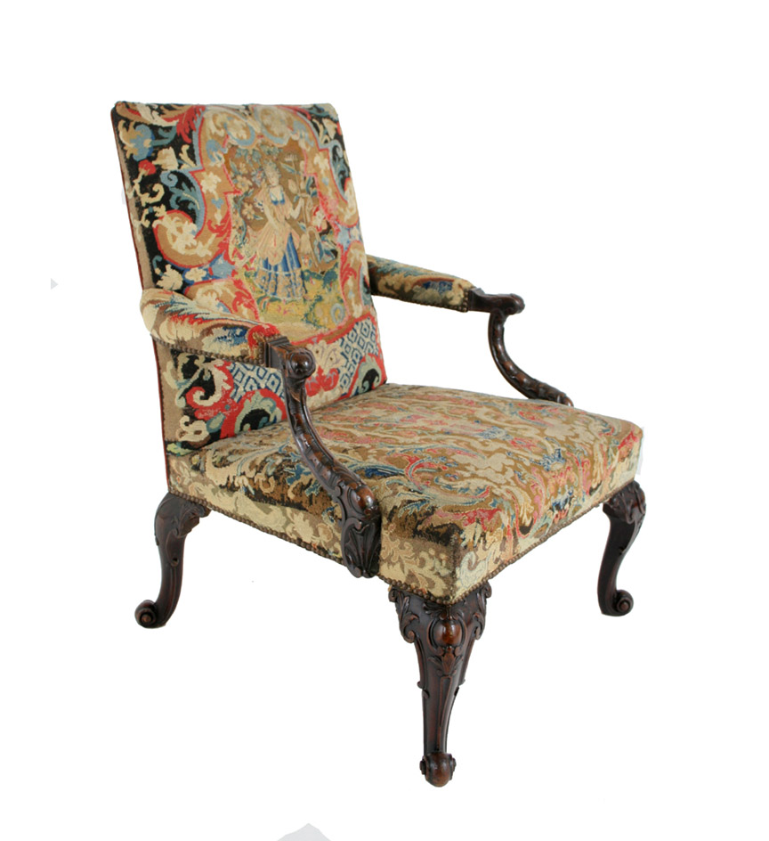 George III carved mahogany Gainsborough chair with needlework upholstery, the downswept molded arms carved with C-scroll and cabochon clasps, the cabriole legs similarly ornamented with scrolled feet.  French 18th c. needlework reconstructed.  Provenance:  The Edward James Collection, West Dean Park, Christie's London, June 1986.