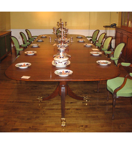 A George III mahogany three pedestal dining table with two sets of associated leaves, the center pedestal of a later date.   The table has two sets of leaves, one narrow and one wide.