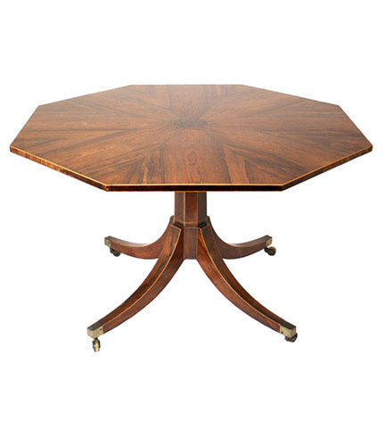 A Regency rosewood octagonal center table, the top with radiating veneers and boxwood strung border, on an octagonal standard continuing to four splayed legs terminating in casters.