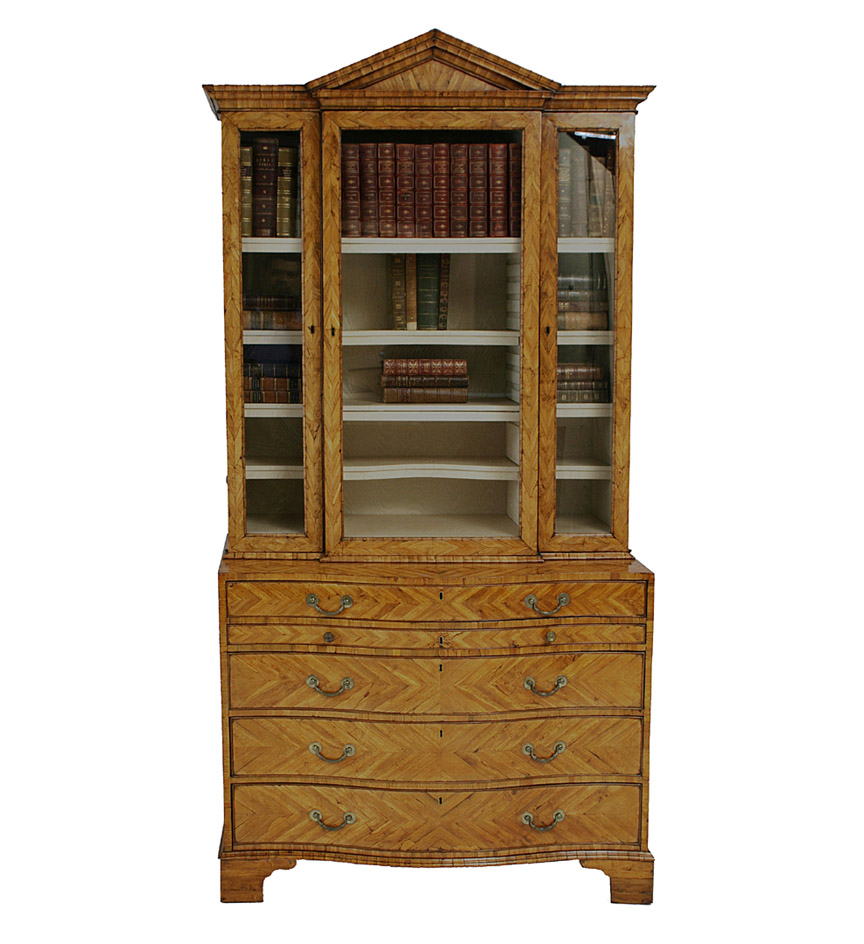 A rare George III cocus-wood cabinet-on-chest, veneered overall in lozenge patterns, the cornice with central pediment above a glazed door, flanked on each side by a narrow glazed door, the lower section with a drawer above a shallow drawer with ratcheted slope, above three drawers, on bracket feet.