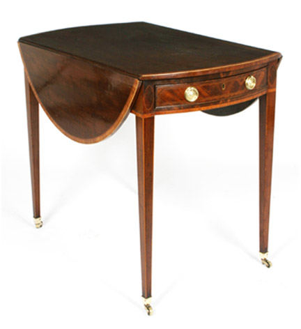 A George III mahogany oval pembroke table with satinwood banded top over a single drawer, raised on tapering legs ending in casters.