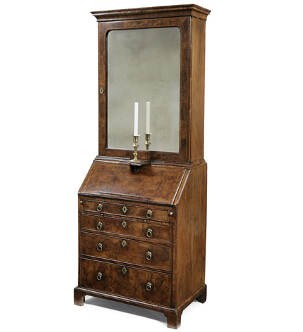 A George I walnut bureau bookcase, the molded cornice above a cross-banded mirrored door retaining its original beveled plate; the lower sectionw ith a  fall-front enclosing a fitted interior, avoe a slide and four graduated drawers, raised on bracket feet.