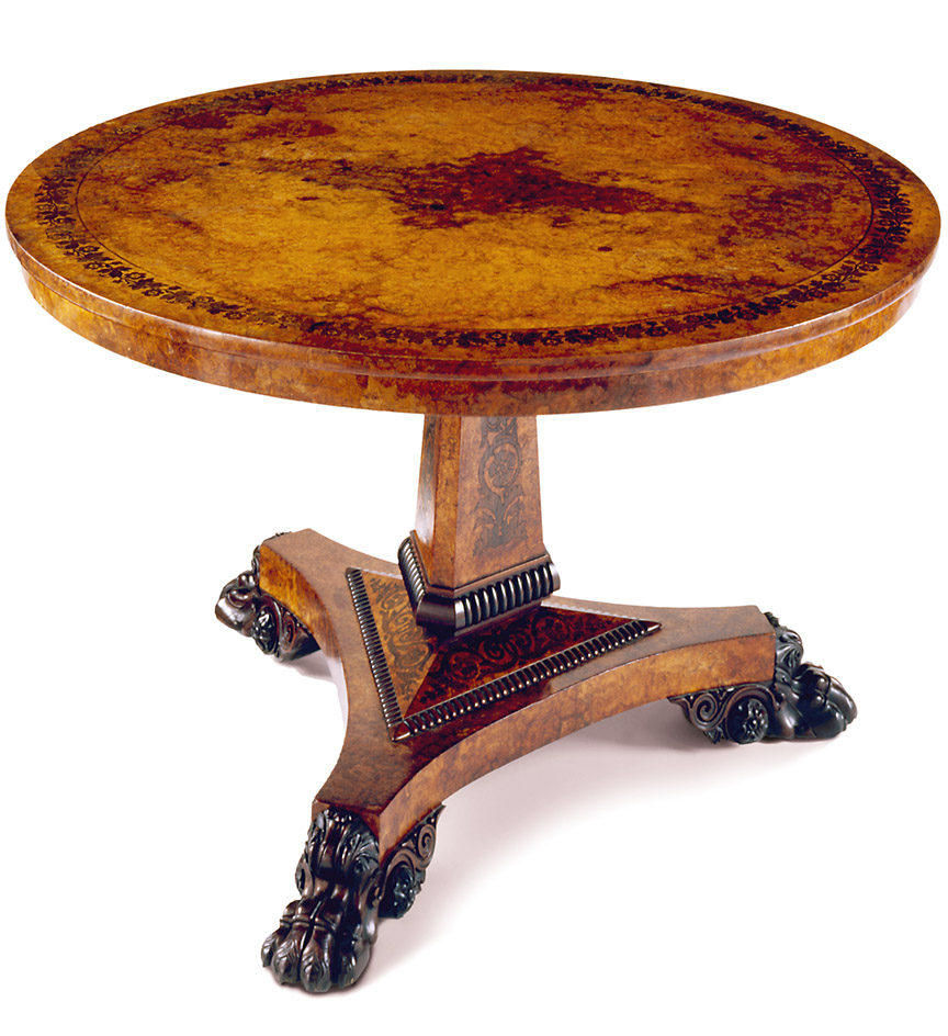 Regency amboyna center table, in the manner of George Bullock, the top with a scrolling rosewood inlaid foliate border, raised on a tri-form column with rosewood molding and inlay, on carved paw feet.