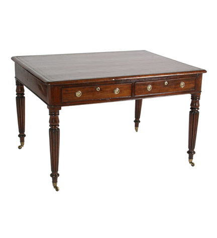 A small scale William IV mahogany writing table with inset leather top over a two-drawer frieze, raised on baluster and reeded tapering legs.