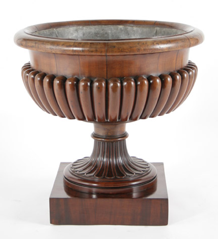A good Regency mahogany wine cooler of gadrooned campana urn form, on a square plinth base ending in casters.