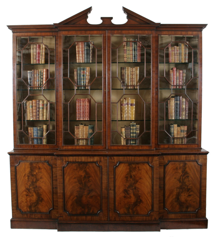A George III and later mahogany breakfront bookcase.  The bookcase with a broken arch pediment over four honeycomb mullioned doors, the lower section comprised of paneled cabinet doors, some revealing stacks of drawers.  Top associated and perhaps of later date.