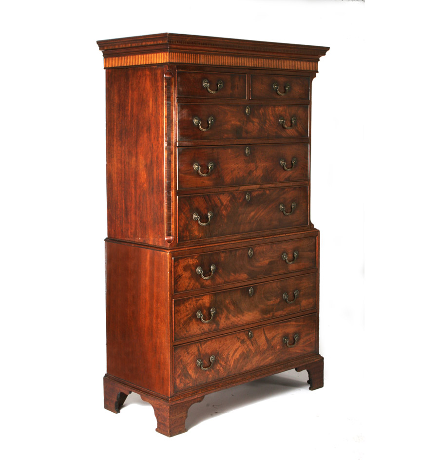 A George III mahogany chest on chest, the cavetto molded cornice with blind dentil molding above a blind fluted frieze, the upper section with chamfered corners over a lower section resting on bracket feet.  Original brass hardware.