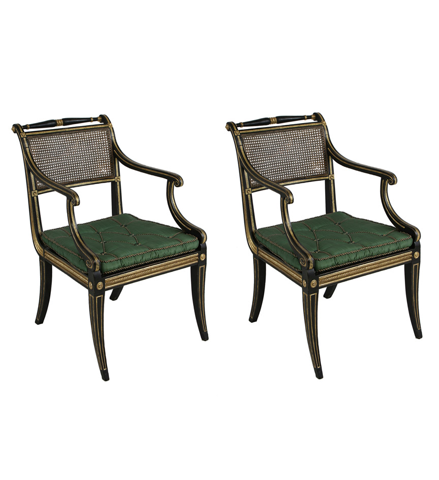 A fine pair of early Regency black painted and parcel gilt open armchairs with caned back panels, scrolled arm terminals, caned seats with loose cushions and sabre legs.