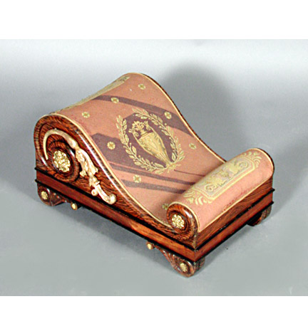 Pair of Regency faux grained rosewood scrolling footstools in the Grecian taste, with raised parcel gilt lotus flower decorated side panels and gilt metal flowerhead mounts, on scrolled feet and upholstered in 19th century neo-classical motif needlepoint.  These stools incorporate design motifs illustrated in George Smith's published 
