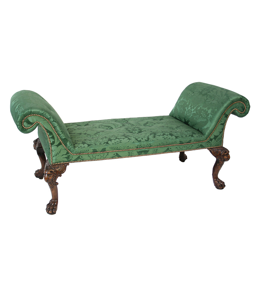 A good George II large upholstered padouk wood  roll-arm window bench raised on lion-mask carved cabriole legs ending in hairy paw feet; probably Irish.   A settee, with nearly identical legs, is illustrated as plate 74 in 