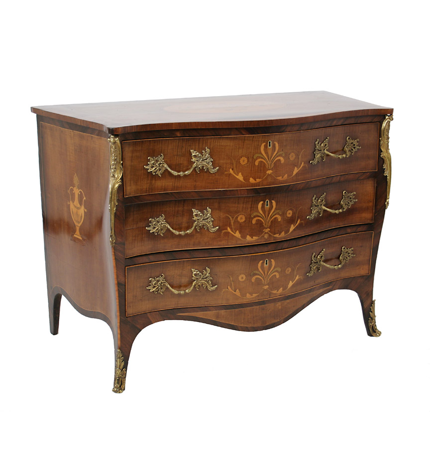 A George III ormolu mounted serpentine commode in the manner of Henry Hill of Marlborough, executed in tulipwood, harewood, rosewood, greenheart, holly and satinwood; the drawers inlaid with acanthus and anthemion, with inlaid urn side panels, and a top oval reserve of flowerheads within stylized foliage. 