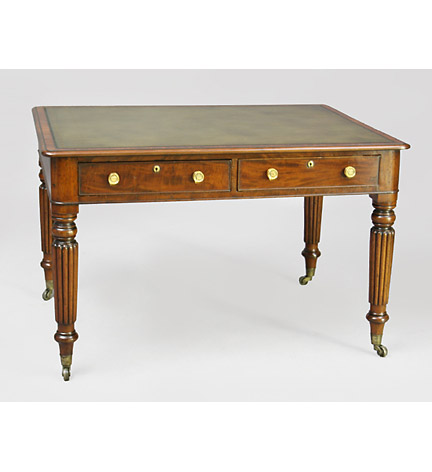 A William IV mahogany partner's writing table, the inset leather top above a two-drawer frieze, raised on ball and reeded legs ending in brass casters.